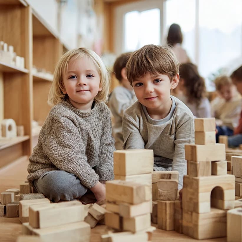 Zwei Kinder sitzen auf dem Boden und spielen mit Holzklötzen