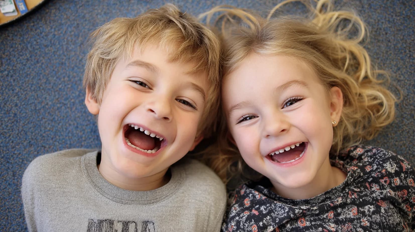 Zwei Kinder schauen und lachen in die Kamera