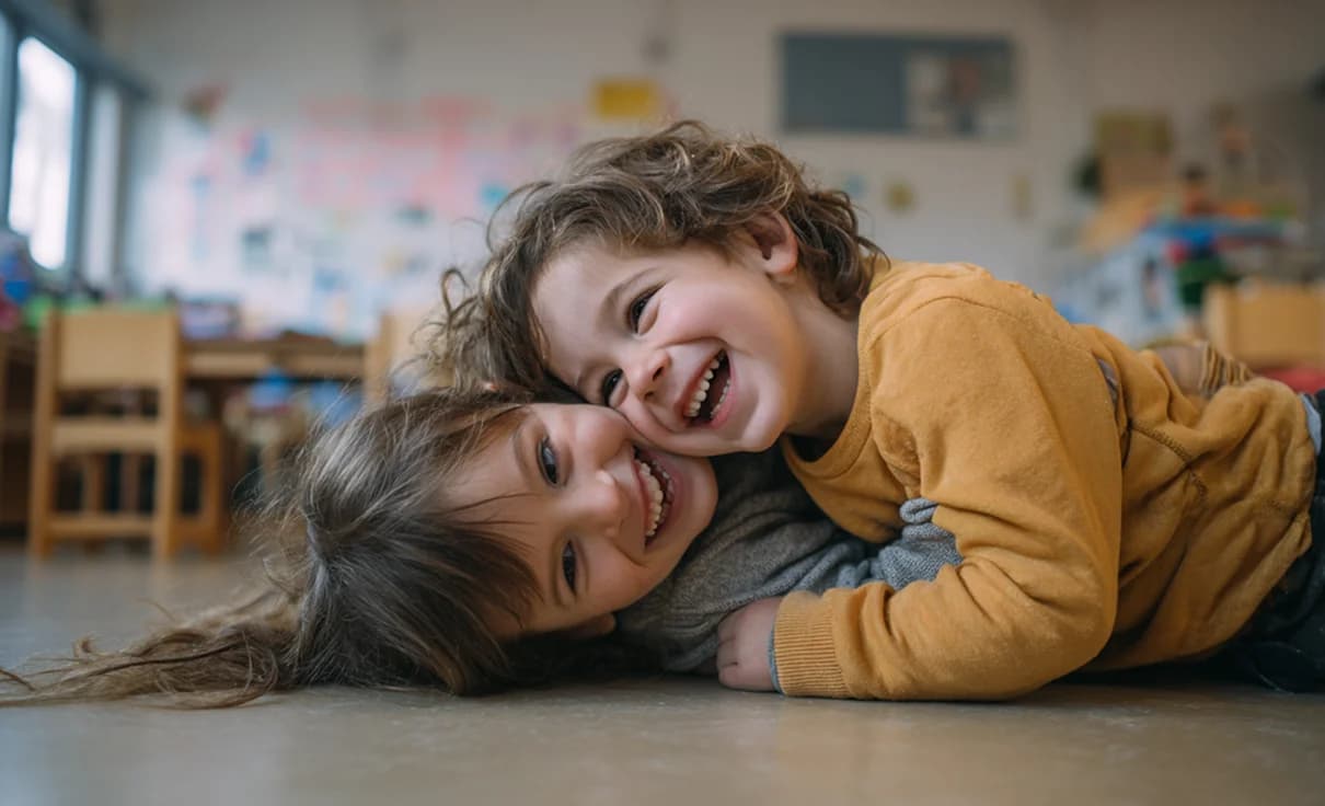 Zwei Lachende Kinder liegen zusammen auf dem Boden